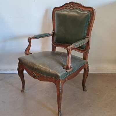 Sillón antiguo de estilo Luis XV, fabricado en madera de nogal y tapizado en cuero verde. Para alquiler de eventos, publicidad, series, películas.