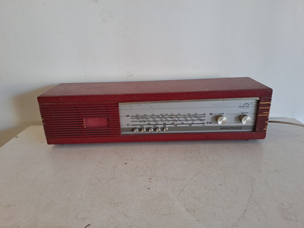 Nordmende Spectra Phonic vintage red radio from the 1960s, made in Germany. It is a desktop radio with AM/FM tuner and a distinctive red or wood finish depending on the version. Rental for events, advertising, series, films.