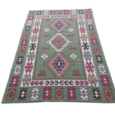 Turkish green wool kilim rug with traditional geometric patterns in red, white and brown for rent for events, advertising, series and films.