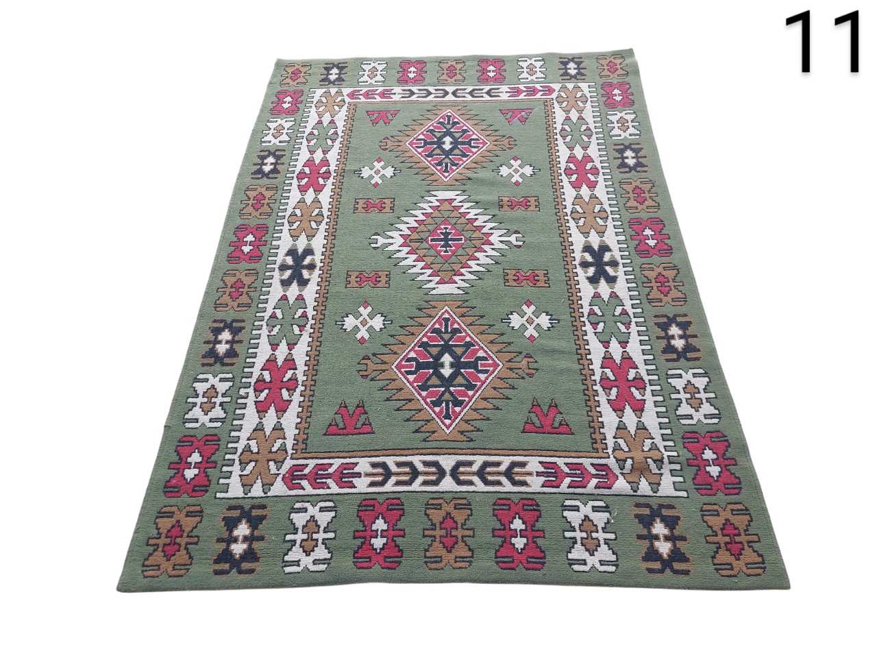 Turkish green wool kilim rug with traditional geometric patterns in red, white and brown for rent for events, advertising, series and films.