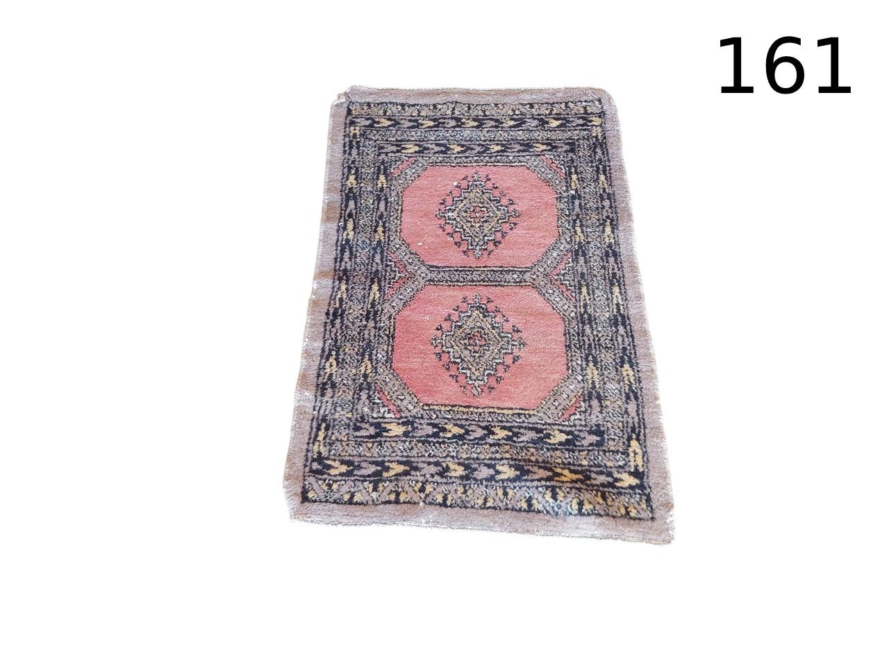Vintage wool rug, possibly of Pakistani or Turkish origin, featuring a geometric bukhara-style design in shades of pink and greyish blue, rented for events, advertising, films and series.