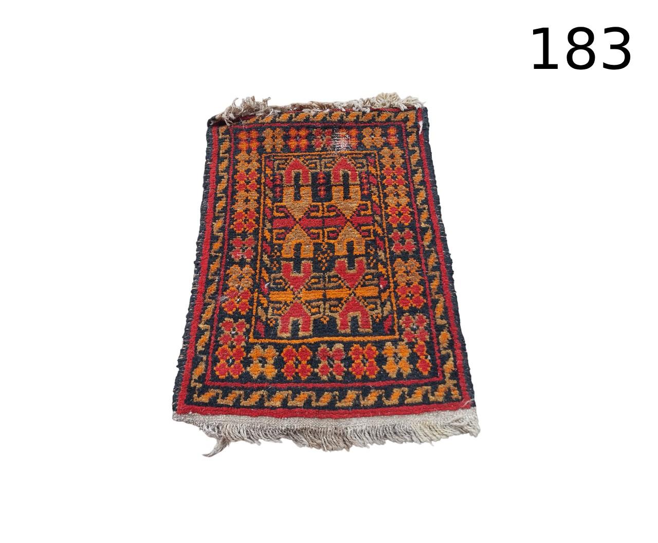 Hand-woven woollen baluchi rug with geometric patterns and traditional motifs in red and blue for hire for events, advertising, films and shows.