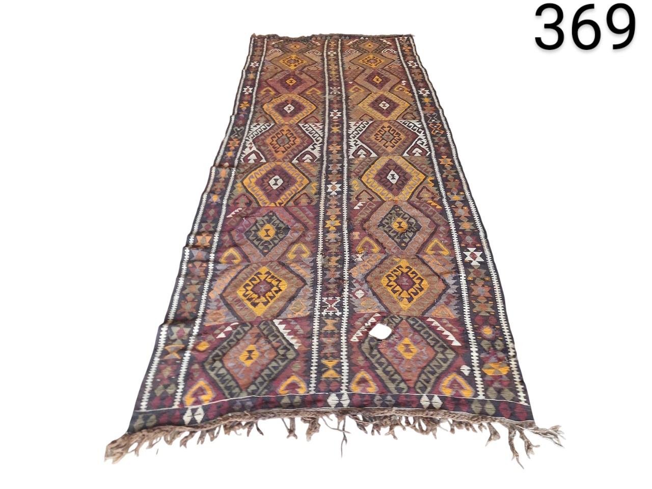 Hand-woven vintage Turkish Kilim rug with geometric patterns in brown, burgundy and orange tones for rent for events, advertising, films and series.