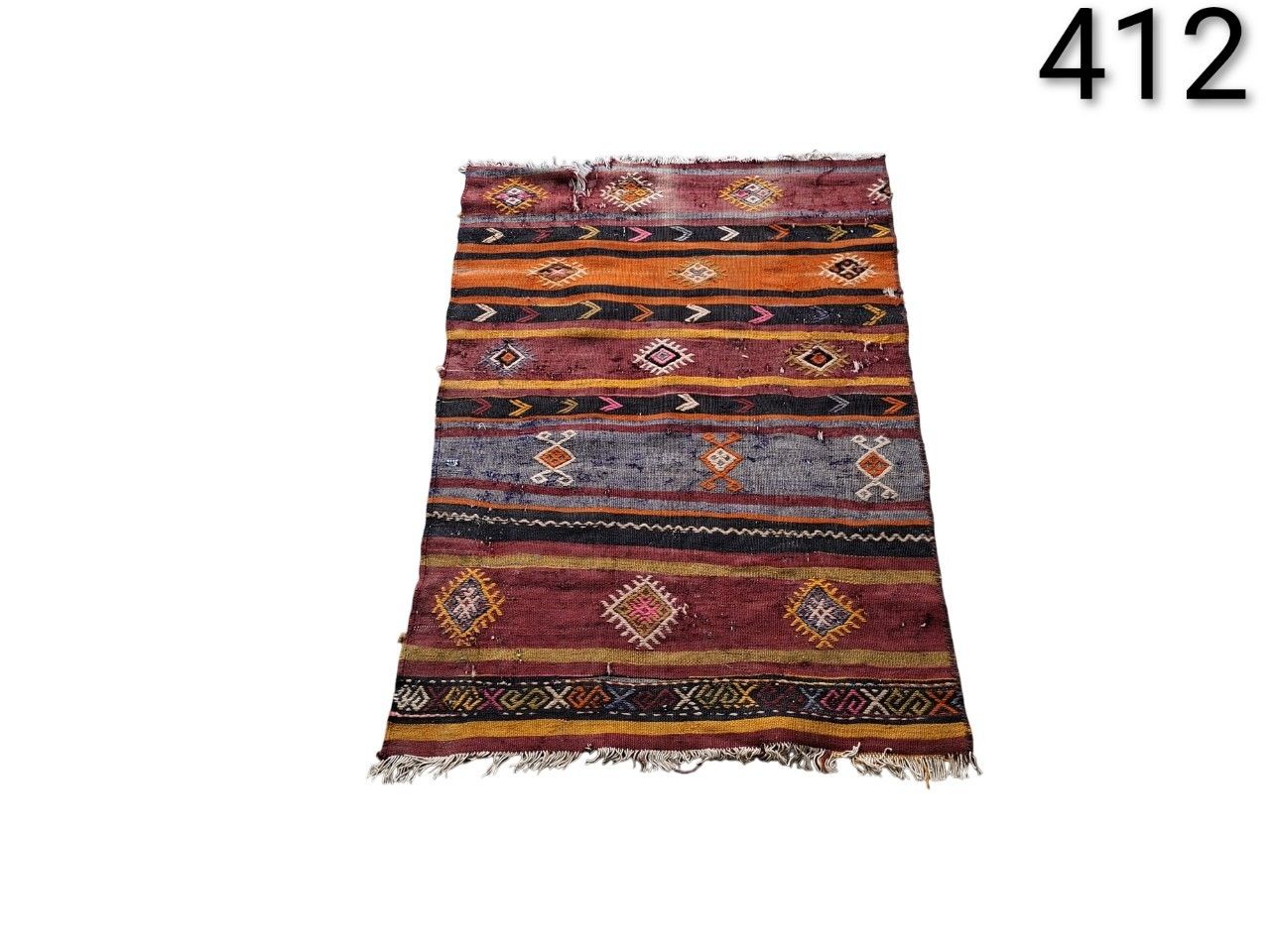 Alfombra Kilim turca vintage tejida a mano con un patrón de rayas geométricas en tonos rojos, naranjas y marrones alquiler para eventos, publicidad, peliculas y series