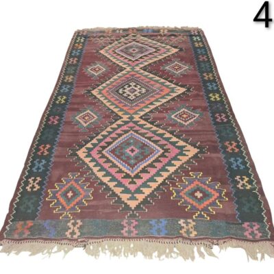 Hand-woven wool Kilim rug, with a traditional geometric design in shades of brown, pink and green, for rent for events, advertising, films and series.