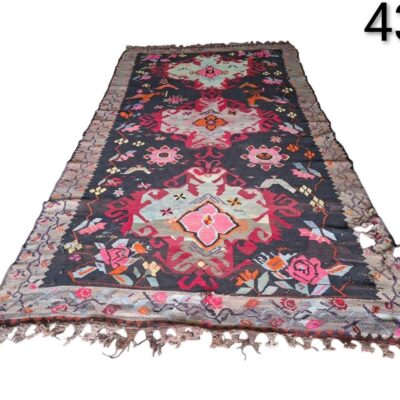Handmade vintage Turkish Kilim rug, possibly from the Kars or Karabağ region, with a dark background and colourful floral or geometric motifs, for rent for events, advertising, films and series.