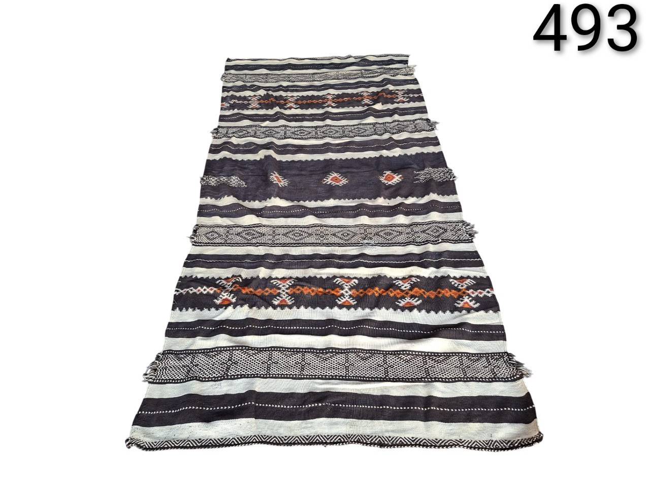 Moroccan Kilim carpet with black and cream stripes and orange geometric patterns for rent for events, advertising, films and series.