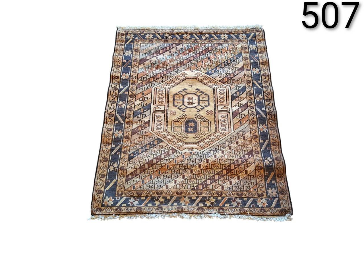 Traditional hand knotted woollen rug with a geometric tribal design and central medallion motifs for hire for events, advertising, films and series.