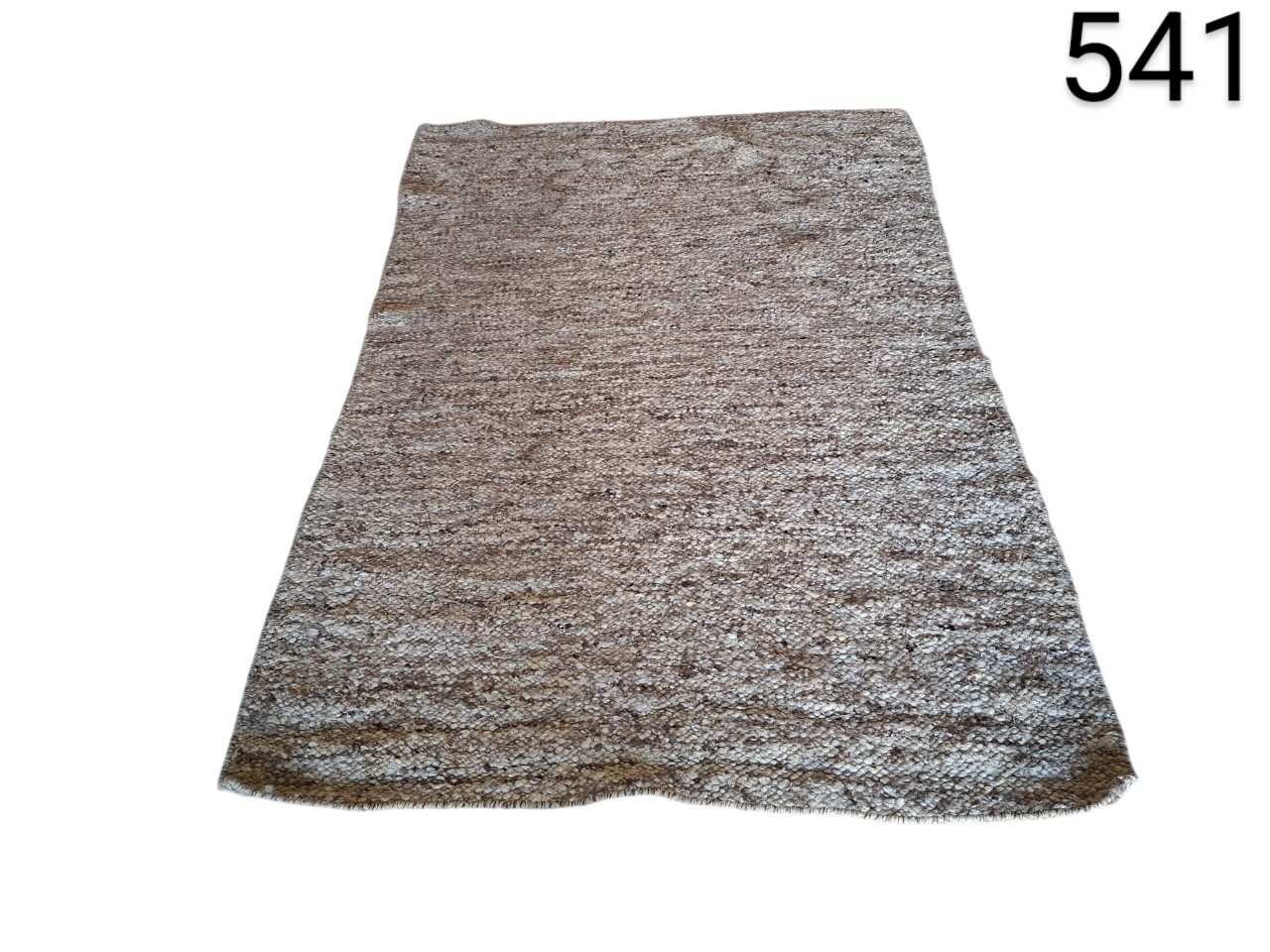 Hand-woven wool rug with a mottled design in neutral tones such as brown and grey, similar to models from brands such as Classic Collection or Linie Design for rent for events, advertising, films and series.