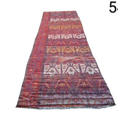 Hand-woven woollen kilim style carpet with geometric patterns in red tones, for rent for events, advertising, films and series.