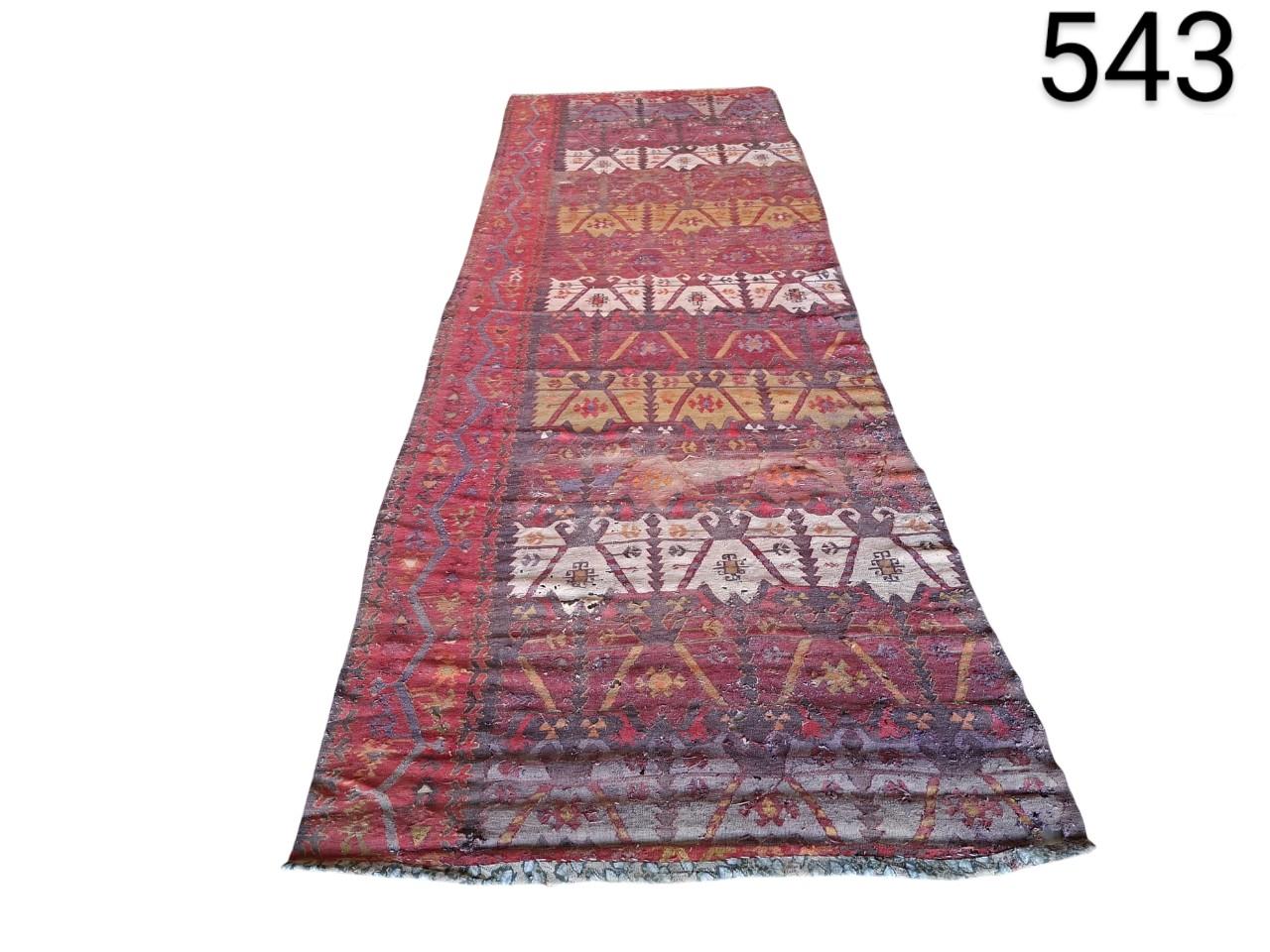 Hand-woven woollen kilim style carpet with geometric patterns in red tones, for rent for events, advertising, films and series.