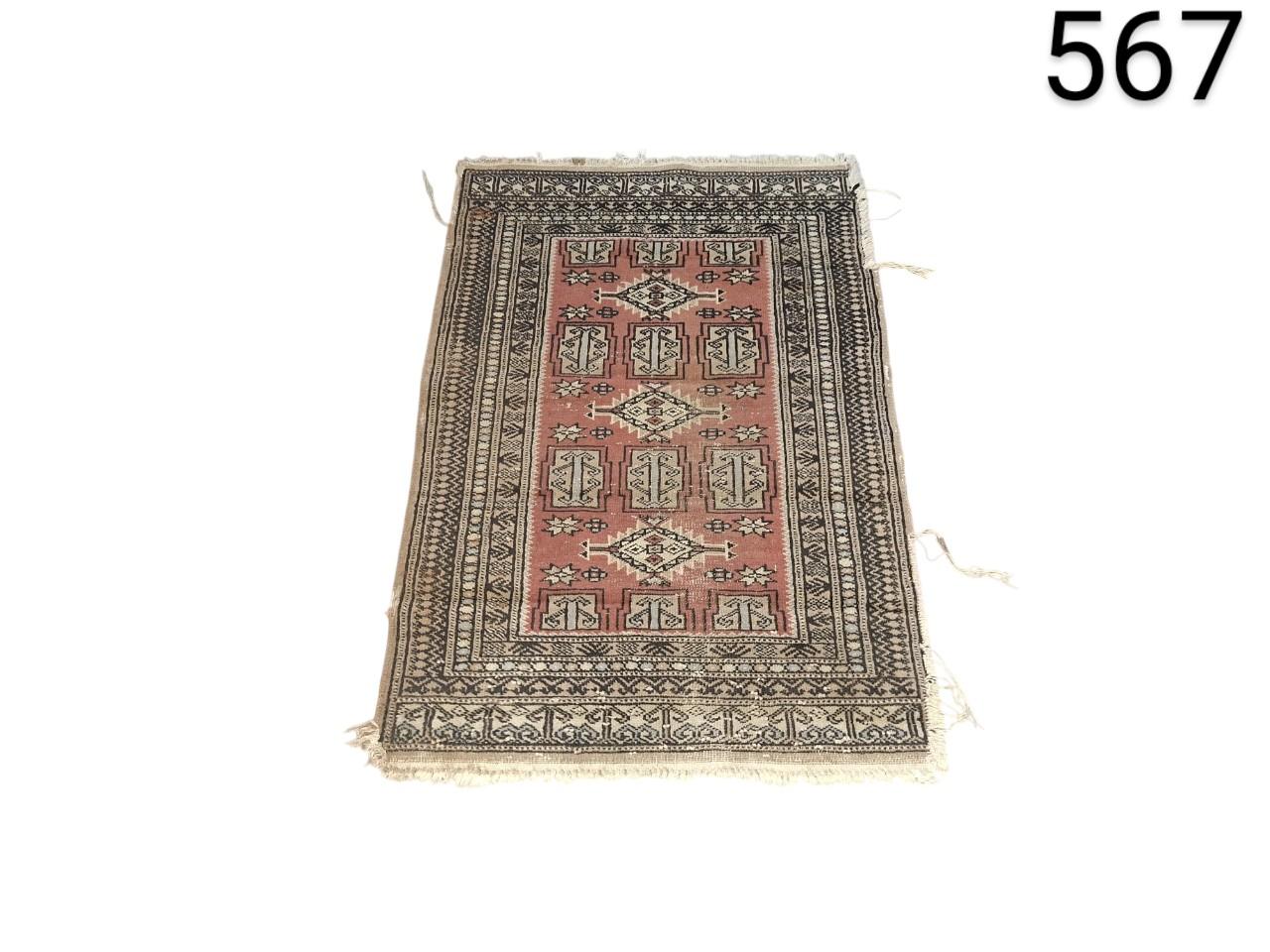 Handmade woollen carpet in Buchara or Pakistan style with geometric patterns in red and black tones for rent for events, advertising, films and series.