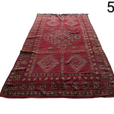Hand knotted woollen afghan rug with a traditional geometric design in red tones for rent for events, advertising, films and series.