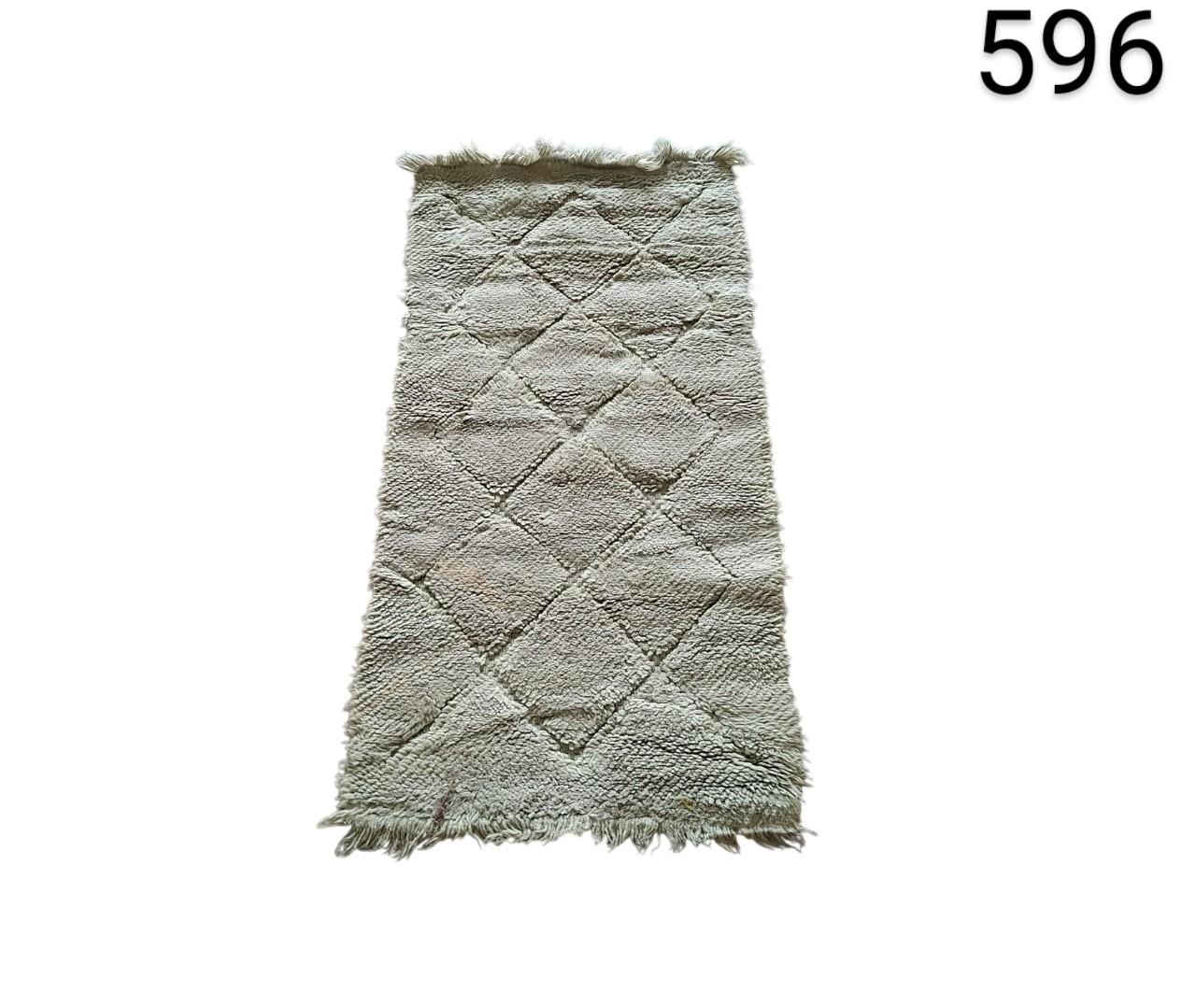 Moroccan hand-woven Beni Ouarain style rug with geometric pattern of diamonds and fringes in ivory or cream tones for rent for events, advertising, films and series.
