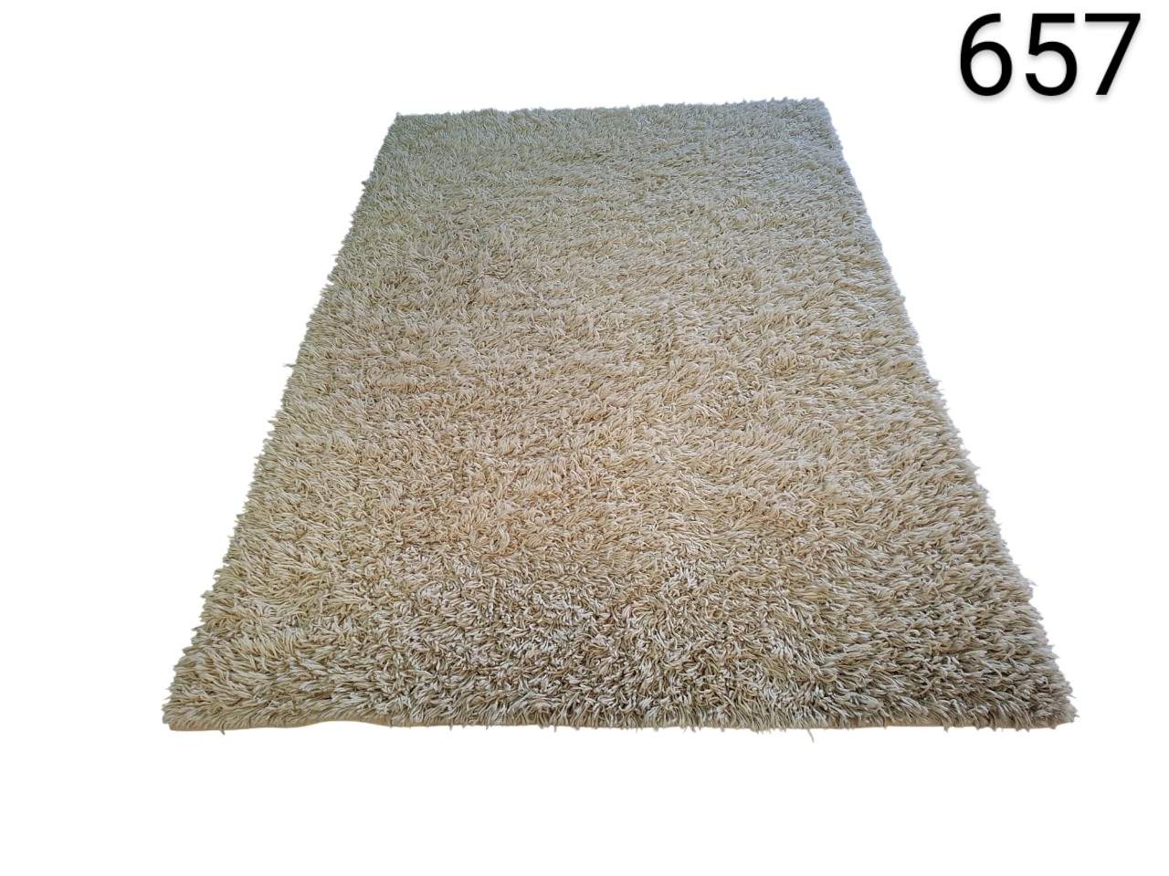 Alfombra de pelo largo, conocida comúnmente como tipo shaggy, es de color beige claro y está fabricada sintéticamente alquilerpara eventos, publicidad, peliculas y series