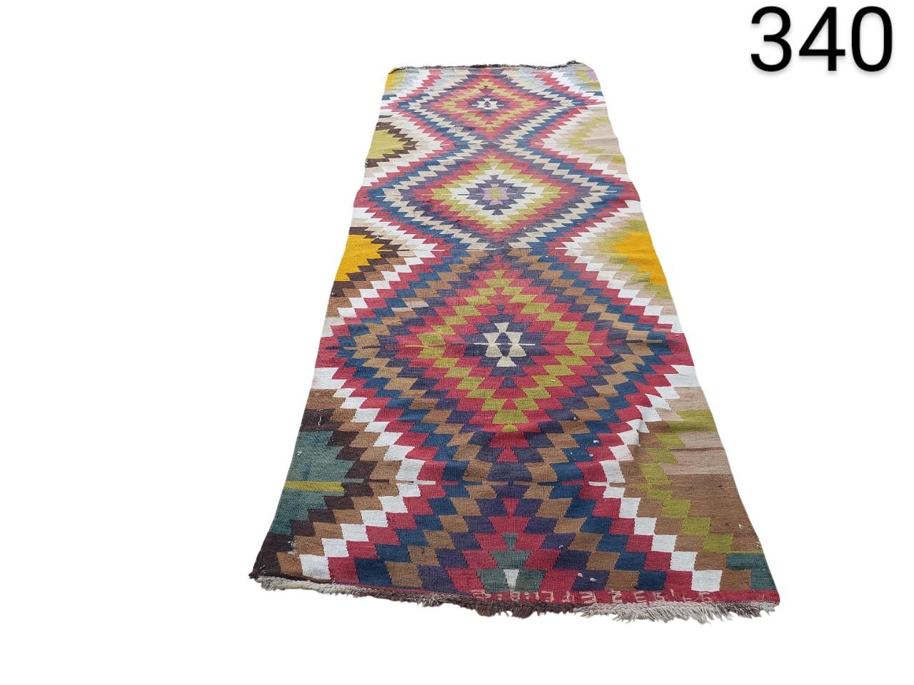 Kilim type carpet of Turkish origin, characterised by its vibrant geometric patterns and its flat weave technique, for rent for events, advertising, films and series.