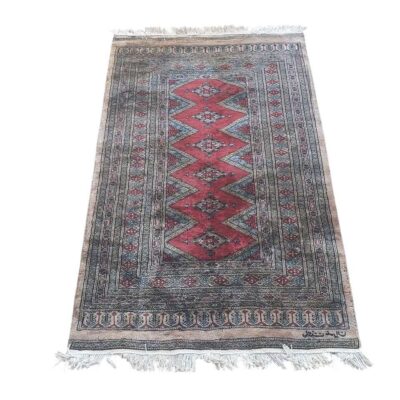 alfombra de lana anudada a mano con un diseño tradicional de Pakistán de colores oscuros negro y rojo. Alquiler para eventos, publicidad, series y peliculas.