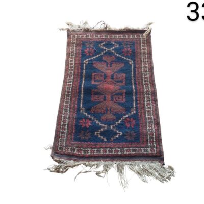 Alfombra pequeña de estilo persa o turco con un diseño geométrico tradicional en tonos azul y rojo alquiler para eventos, publicidad, peliculas y series