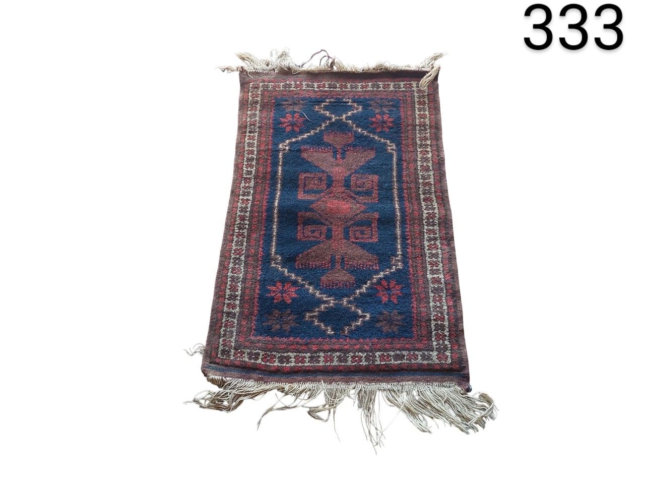 Alfombra pequeña de estilo persa o turco con un diseño geométrico tradicional en tonos azul y rojo alquiler para eventos, publicidad, peliculas y series