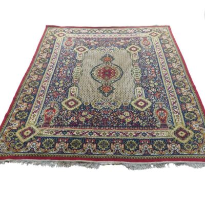 Alfombra de estilo persa con un diseño tradicional de medallón central y motivos geométricos en colores rojo, azul y beige alquiler para eventos, publicidad, peliculas y series