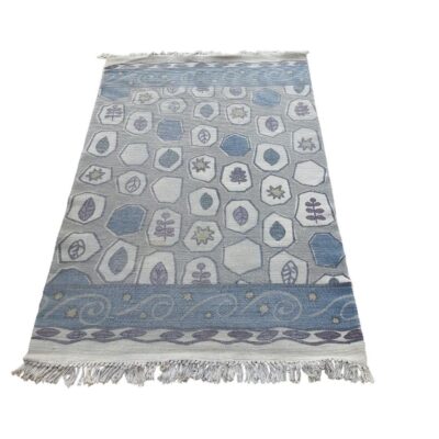 Hand-woven kilim type rug with geometric patterns in blue and grey tones, and fringes at the ends for rent for events, advertising, films and series.