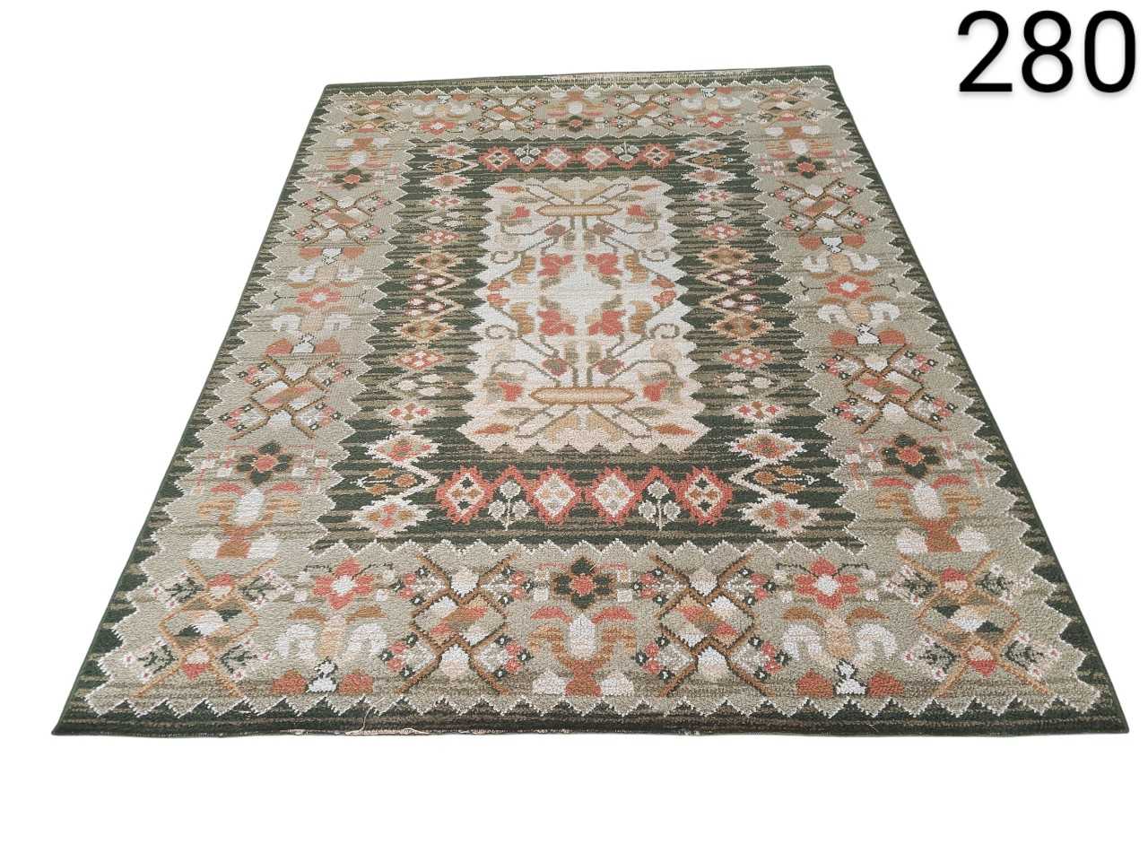 Alfombra tipo kilim tejida a mano con patrones geométricos tradicionales en tonos verdes, beige y naranjas alquiler para eventos, publicidd, peliculas y series
