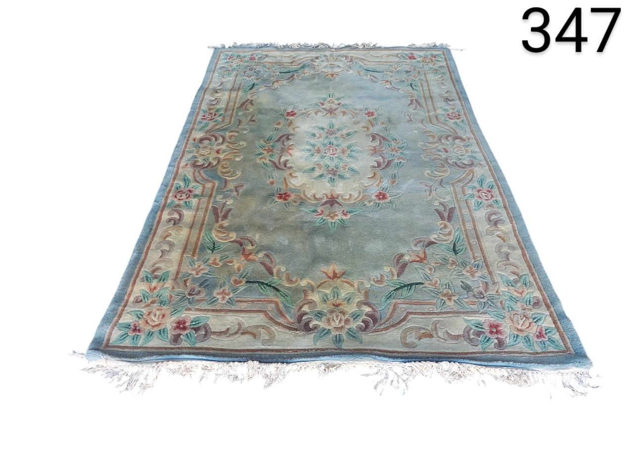Traditional French Aubusson wool rug with floral motifs in pink, beige and green tones on a blue background for rent for events, advertising, films and series.
