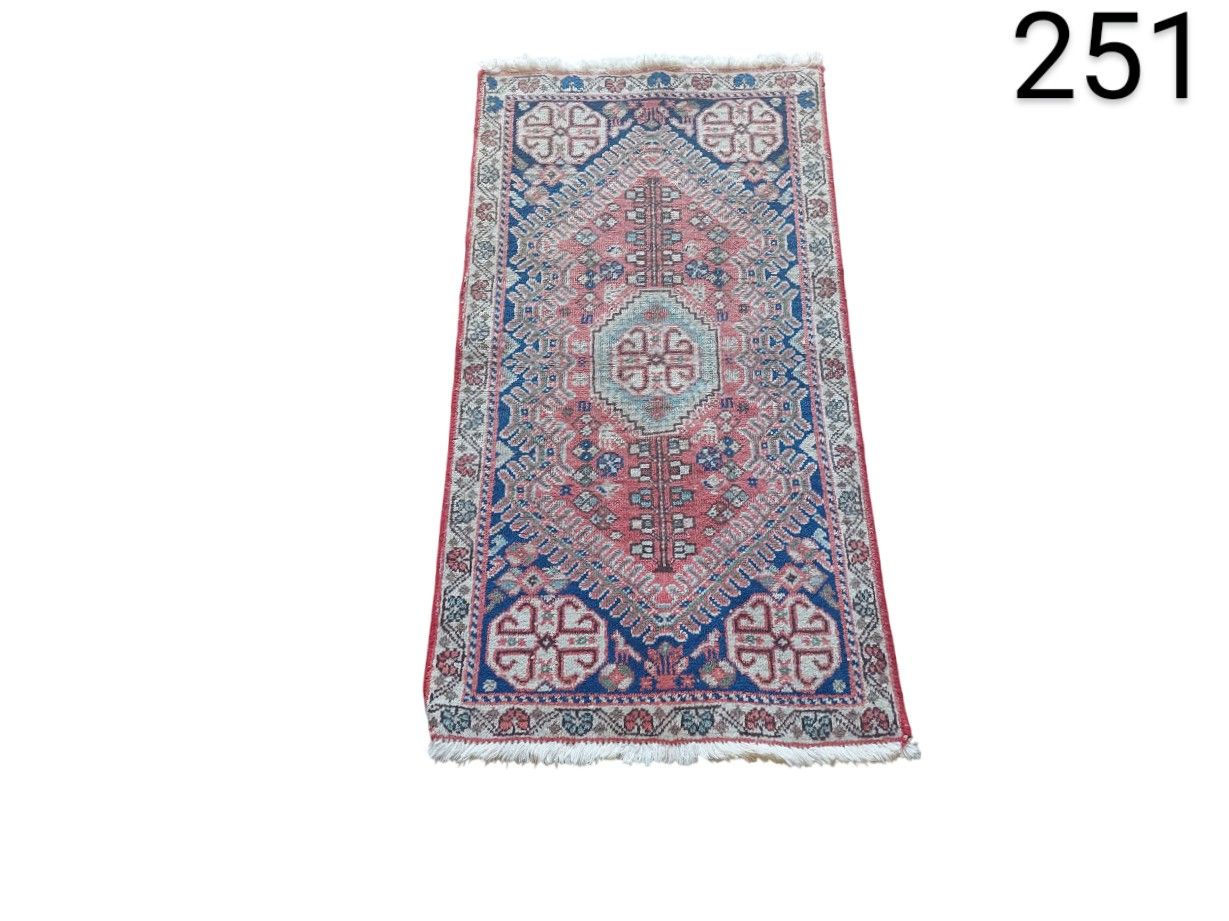 Hand-woven antique turkish rug with a geometric pattern in pink and blue tones for rent for events, advertising, films and series.