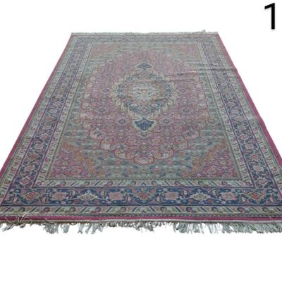 Alfombra es una pieza vintage de lana anudada a mano, posiblemente de estilo turco o persa, con patrones florales tradicionales en tonos rosa y azul.  alquiler para eventos, publicidad, peliculas y series