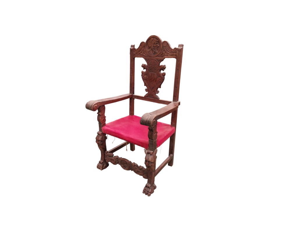 Spanish Renaissance-style armchair featuring a wooden frame carved with heraldic motifs and a seat upholstered in red velvet; available for hire for events, advertising, films and TV series