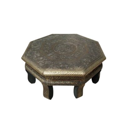 A low-profile table with an octagonal frame and a base supported by curved legs. The entire surface, including the top and the legs, is covered with metal sheets worked using embossing and chiselling techniques, featuring floral and geometric motifs. It is a handcrafted piece of furniture suitable for use as a low side table or as a decorative accent piece.