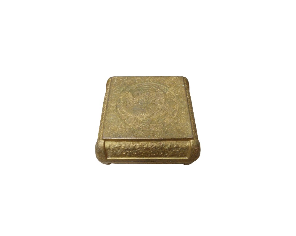 caja de metal con un acabado dorado envejecido, caracterizada por una forma rectangular de bordes redondeados y una superficie superior e inferior completamente decorada con finos grabados tradicionales que presentan motivos ornamentales y figuras circulares en relieve alquiler para eventos, publicidad, peliculas y series