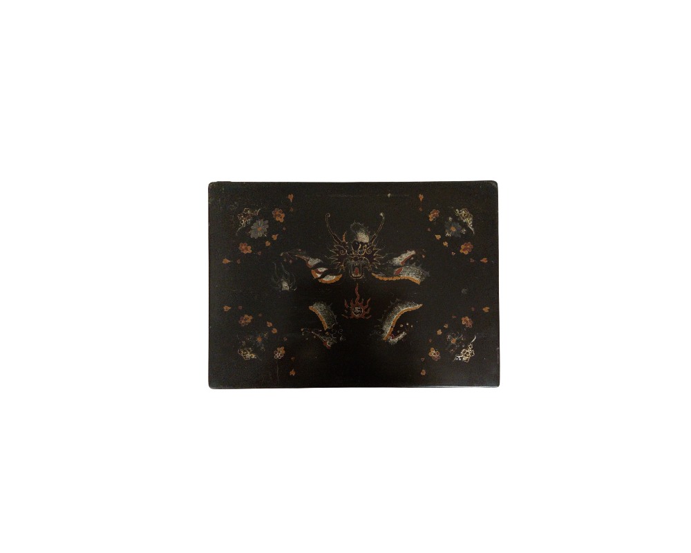 mesa auxiliar pequeña de tonos oscuros, caracterizada por un tablero superior rectangular decorado con finos motivos dorados, soportes laterales curvados de diseño estilizado y patas con terminales metálicos alquiler para eventos, publicidad, peliculas y series