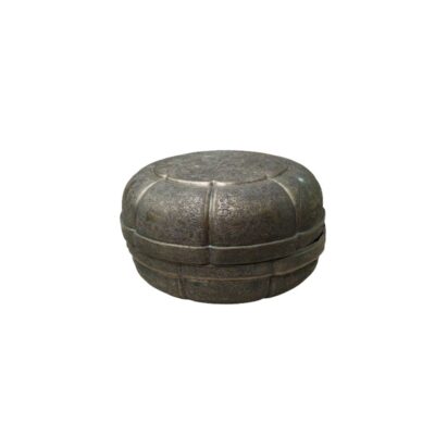A metal container with a dark, distressed finish, characterised by a circular shape with lobed sections along its outline and a surface entirely covered in finely crafted ornamental engravings; available for hire for events, advertising, films and TV series