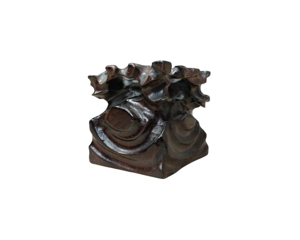 A pedestal crafted from dark wood, distinguished by its carvings of organic, flowing forms that evoke natural elements or rock formations. Unlike traditional geometric bases, this one features a more irregular and sculptural design, ideal for supporting decorative pieces that require a stand with character of its own – available for hire for events, advertising, films and TV series.
