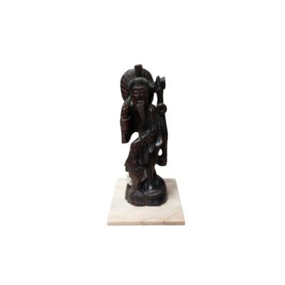 A figure carved from dark wood with a polished finish, characterised by its depiction of a traditional, elderly-looking, smiling figure, dressed in intricately detailed robes, wearing a hat or carrying an accessory on its back, with a fish or decorative object at its feet, all mounted on a solid rectangular base of light, veined marble. Available for hire for events, advertising, films and TV series.