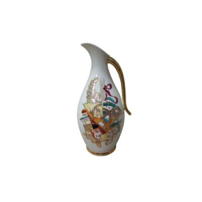 An elegant porcelain jug with a white base, a rounded body and a sloping spout, decorated with a central design inspired by the world of opera, featuring instruments and graphic elements in colourful tones. Available for hire for events, advertising, films and TV series.