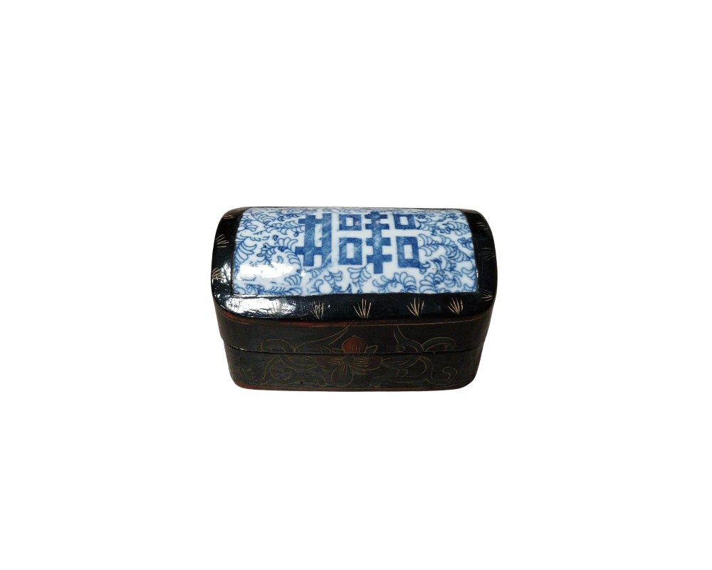 A traditional-style rectangular jewellery box, characterised by its black-lacquered wooden body with subtle floral decorations engraved on the sides. The lid features a central inlay of blue and white porcelain. Hire for events, advertising, films and TV series