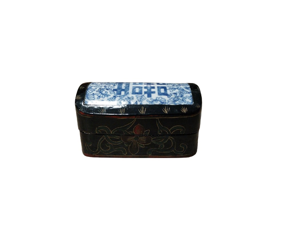 alhajero rectangular de estilo tradicional, caracterizado por su cuerpo de madera lacada en negro con sutiles decoraciones florales grabadas en sus laterales. La tapa destaca por una incrustación central de porcelana azul y blanca alquiler para eventos, publicidad, peliculas y series