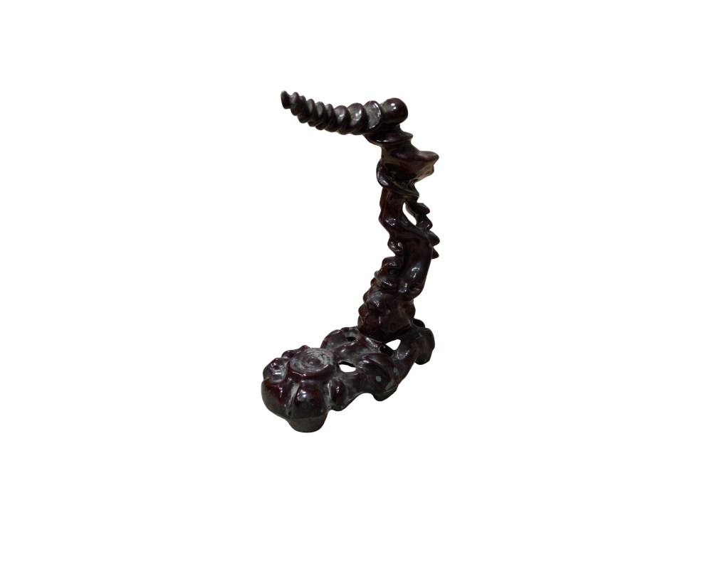 A decorative vertical display stand made from dark wood, featuring carvings that evoke organic, flowing shapes; available for hire for events, advertising, films and TV series