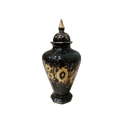 A ceramic or porcelain vase with a glossy black finish and a fluted body, characterised by an elegant floral decoration in golden tones that stands out against its surface, and a matching lid with a pointed top; available for hire for events, advertising, films and TV series