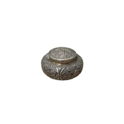 joyero circular de metal con acabado plateado y pátina envejecida, caracterizado por un cuerpo abombado y una tapa superior rehundida, ambos ricamente decorados con complejos relieves de motivos florales y vegetales alquiler para eventos, publicidad, peliculas y series