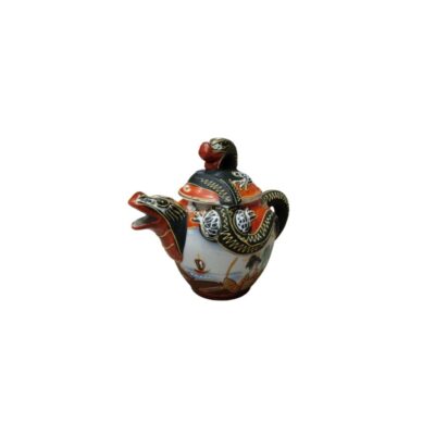 tetera ornamental con un diseño artístico altamente detallado que evoca elementos de la mitología oriental. Destaca especialmente por su pico vertedor, que tiene la forma de una cabeza de criatura mitológica, posiblemente un dragón, un motivo que se extiende hacia la tapa y el cuerpo de la pieza alquiler para eventos, publicidad, peliculas y series