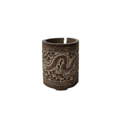 A cylindrical wooden object with a dark brown finish, featuring a carved relief on its outer surface depicting a winding dragon surrounded by cloud-like or stylised motifs, framed by geometric borders; available for hire for events, advertising, films and TV series
