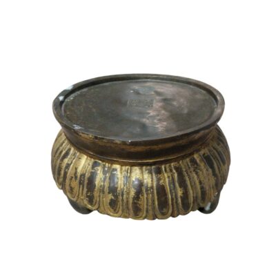 A circular metal object, characterised by a low structure resting on small legs. Its design features a fluted body with a partially gilded finish that contrasts with the dark hue of the metal, and an engraved hallmark can be seen on its upper surface. It is a handcrafted piece with a classic aesthetic, which can be used as a decorative stand to elevate objects or as a traditional ceremonial vessel.