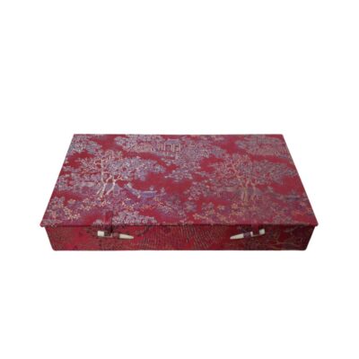 caja rectangular forrada con una elegante tela de tonos rojos y bordados metalizados que representan paisajes y motivos orientales, caracterizada por un diseño alargado y un cierre frontal mediante trabillas de tela y pasadores decorativos alquiler para eventos, publicidad, peliculas y series