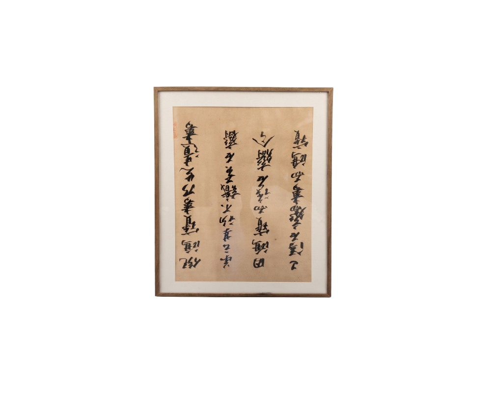 A traditional Chinese calligraphy piece on oatmeal-coloured paper, framed with a slim wooden border and a light-coloured mat, characterised by vertical columns of expressive strokes in dark ink and a distinctive red seal; available for hire for events, advertising, films and TV series