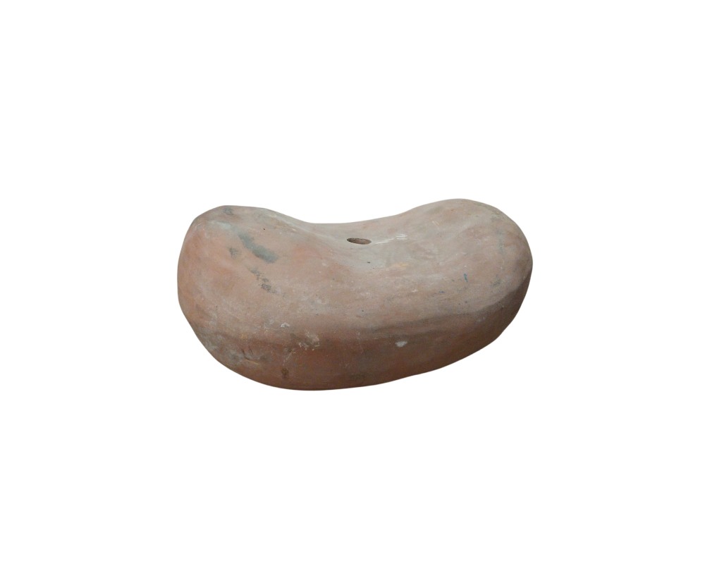 soporte de cerámica con una forma curva y alargada, similar a una almohada o cabezal tradicional, con tonos terrosos y un pequeño orificio perforado en su parte central superior alquiler para eventos, publicidad, peliculas y series