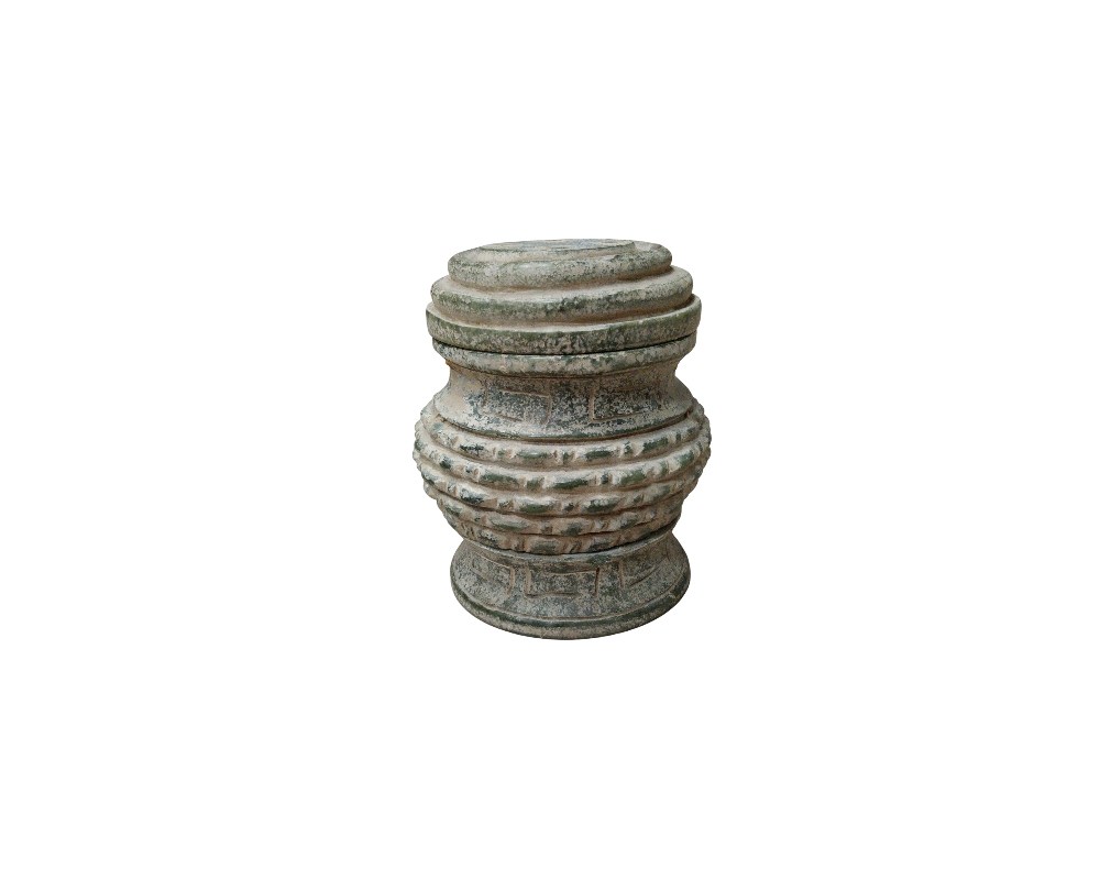 A compact, cylindrical object crafted from stone with a textured finish and weathered tones. It features a segmented structure comprising a snug-fitting lid and geometric decorations carved into its central body. This handcrafted piece, with its austere and traditional aesthetic, serves as an elegant decorative centrepiece or as a specialised container for calligraphy, evoking an antique style. Available for hire for events, advertising, films and TV series.