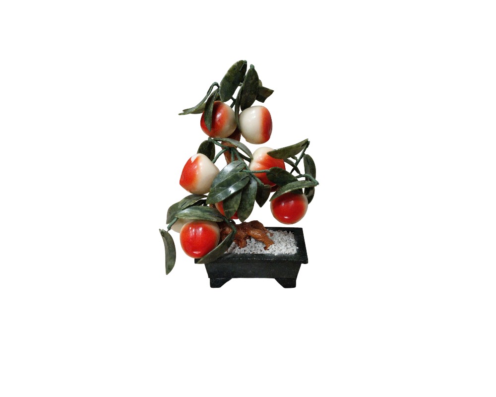 Ornamental bonsai made from minerals or sculpted stones, characterised by a trunk resting on a base that resembles white gravel inside a dark rectangular pot, with green leaves and numerous round fruits in shades ranging from red to white; available for hire for events, advertising, films and TV series